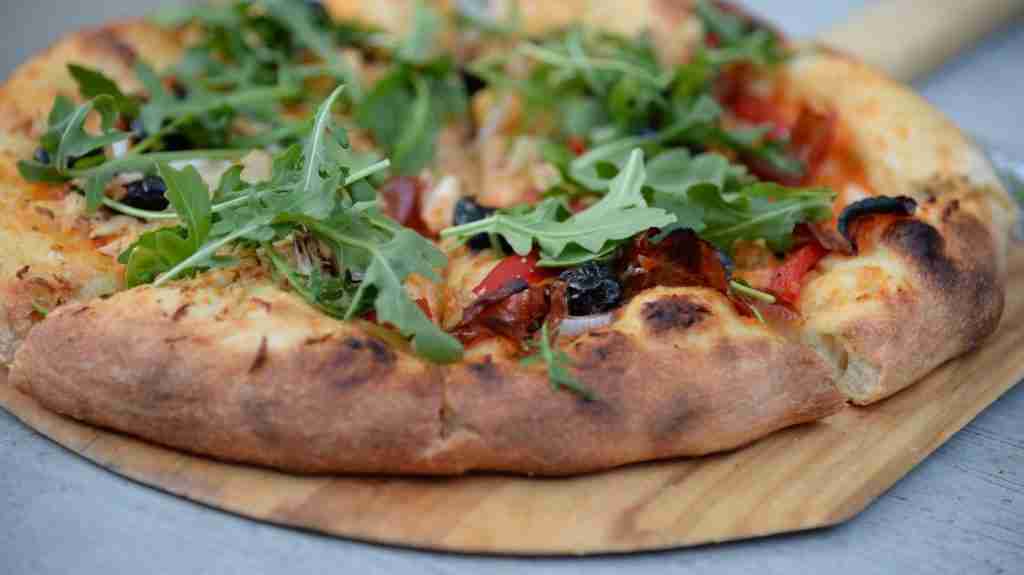 25 Fun Facts About Pizza Hut (From Red Roof to the Crown Crust) 5 pepperoni pizza with green leafed toppings