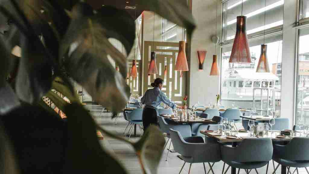 25 Fun Facts About Pizza Hut (From Red Roof to the Crown Crust) 2 woman in front on brown dining table in pizza hutand chairs inside building