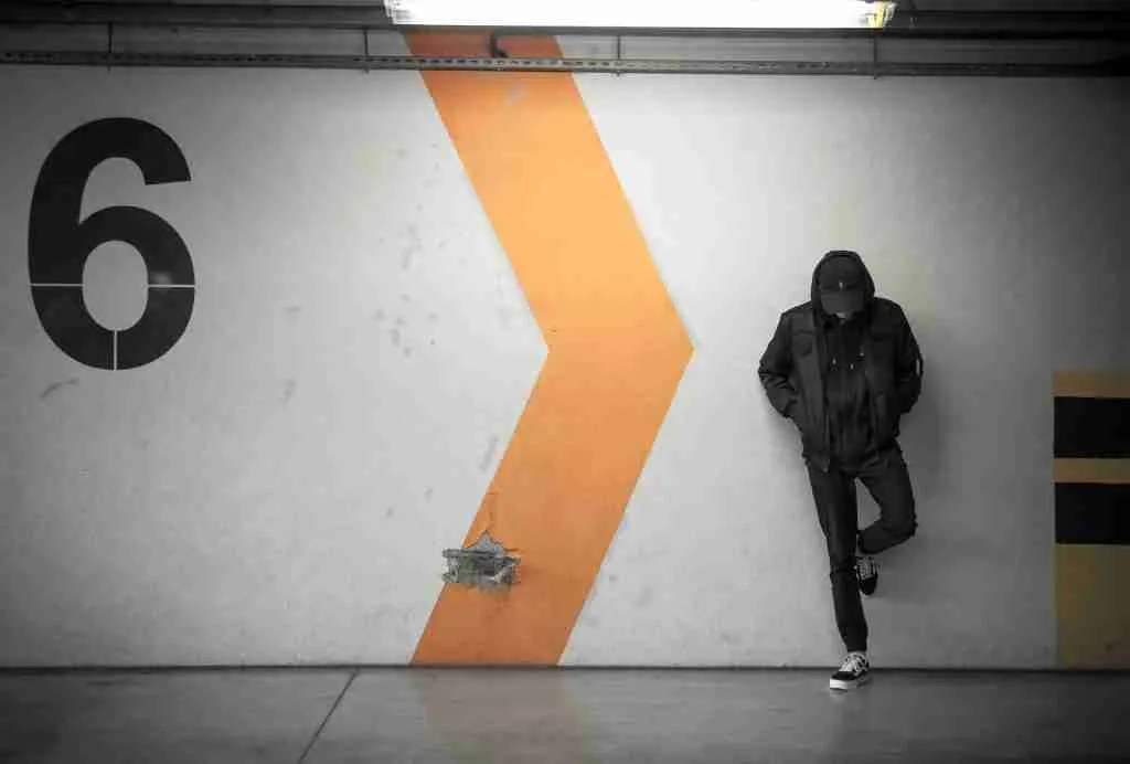 man leaning on white wall with number 6 written on side.