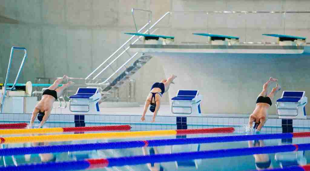 22 Fun Facts About Swimming You Must Know 2 Image of three swimmers jumping on swimming pool : Fun Facts About Swimming