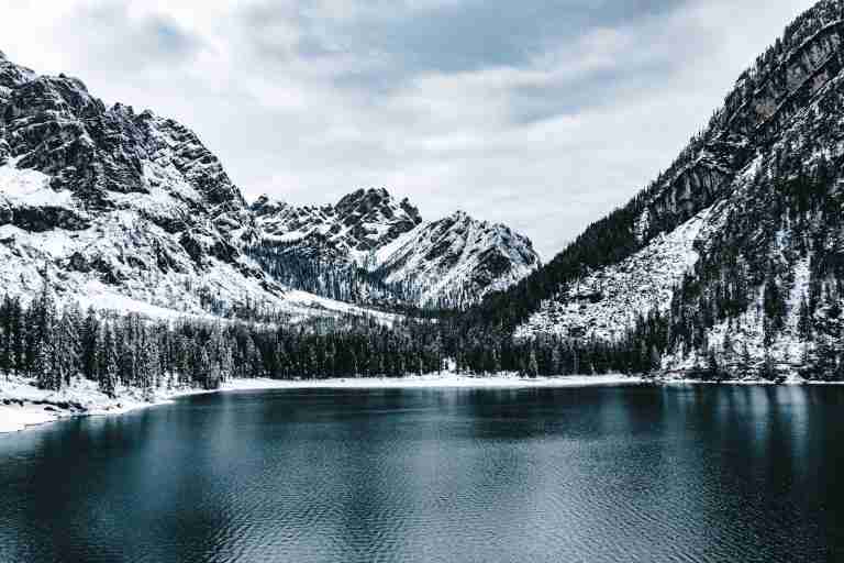 snow covered mountain near body of water during daytime