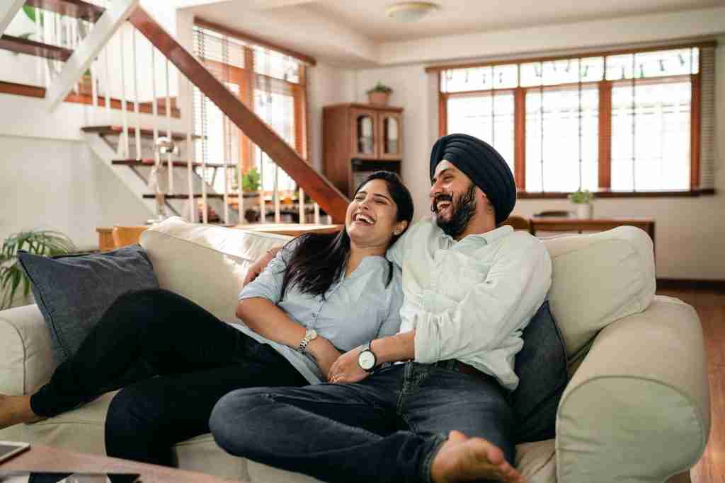 22 Fun Facts About Gemini You Need to Know 1 Laughing young Indian couple exploring fun facts about Gemini while watching a comedy at home.