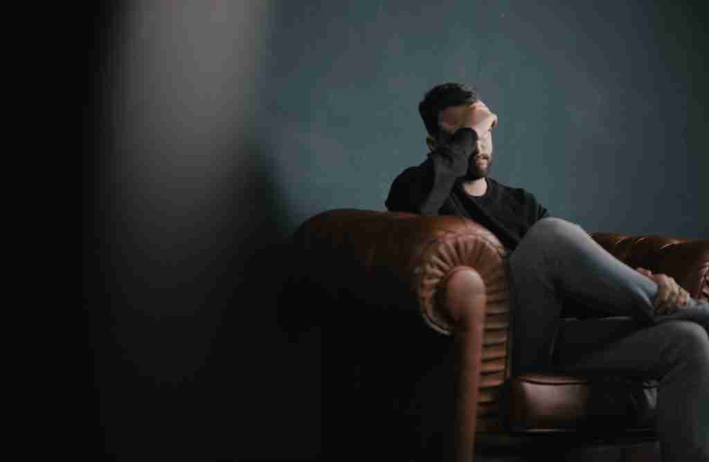 25 Facts About Kanye West You Didn't Know 5 a man holds his head while sitting on a sofa