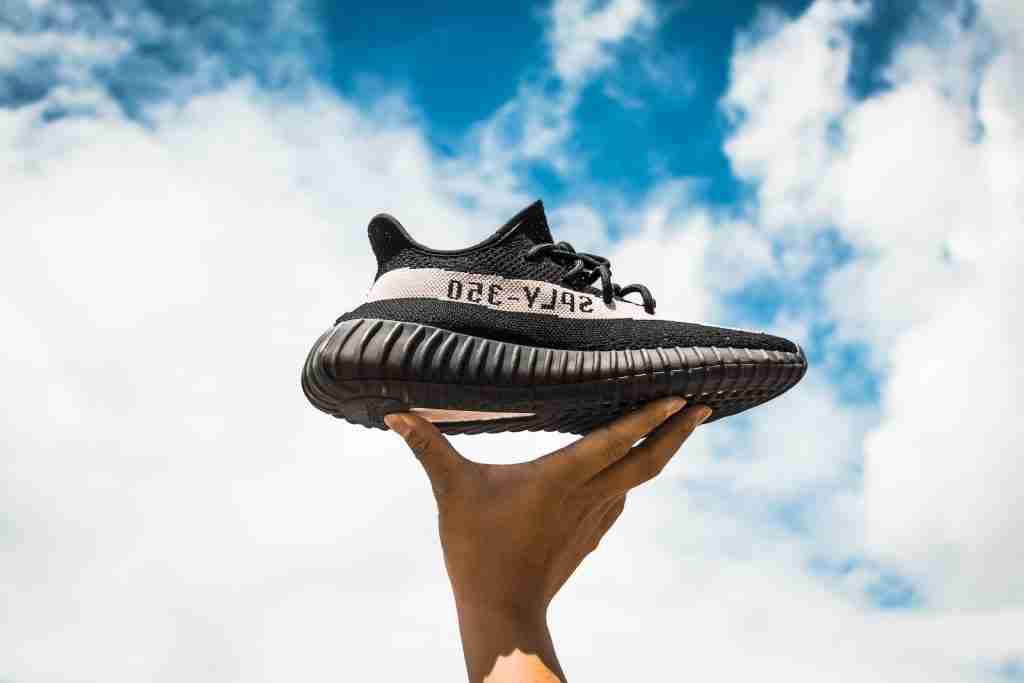 25 Facts About Kanye West You Didn't Know 2 unpaired adidas Yeezy Boost 350 V2 shoe on person's hand