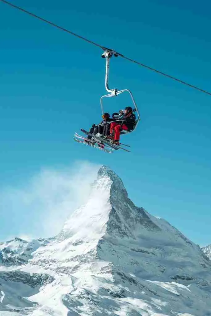 red and black cable car over snow covered mountain