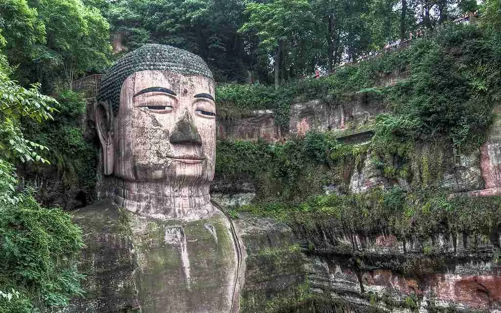 27 Interesting Facts About China You Never Knew 2 Stone-carved giant statue adorned with lush greenery – uncovering interesting facts about China's cultural marvels.