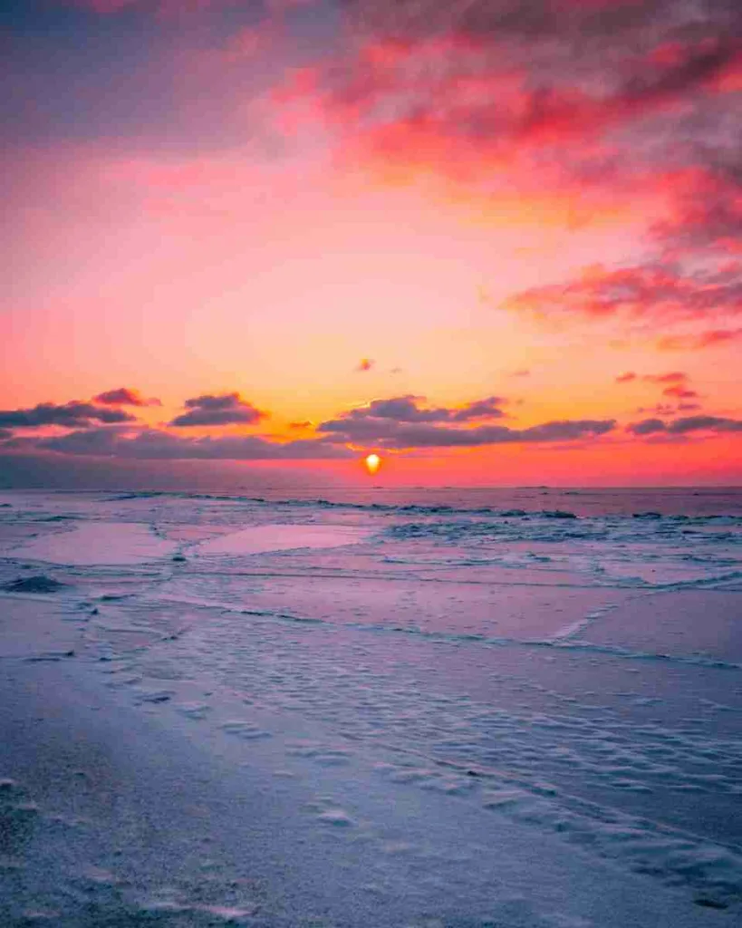 ocean waves crashing on shore during sunset