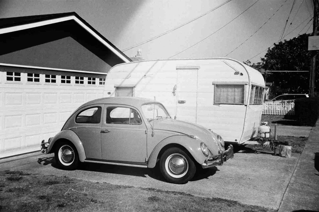 23 Fun Facts About Henry Ford 4 grayscale photo of Volkswagen Beetle coupe beside travel trailer parked in front of garage