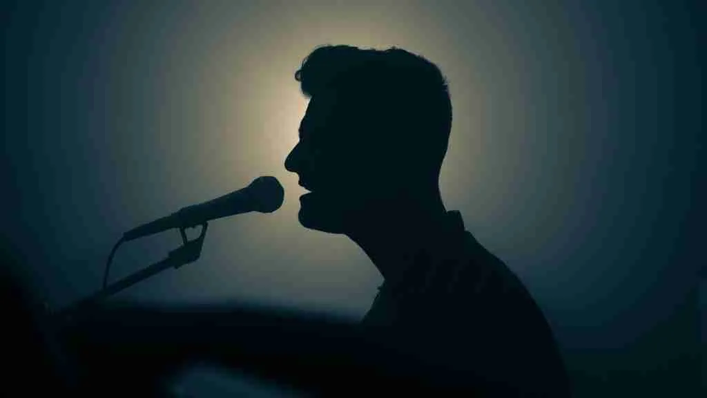 a silhouette of a man singing into a microphone
